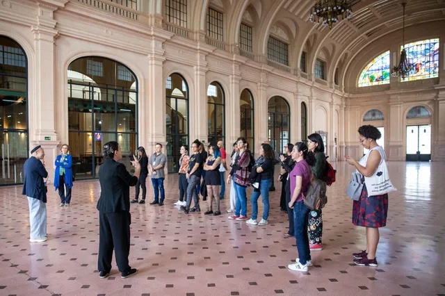 Um grupo de pessoas está na Estação das Artes da Sala São Paulo, ouvindo os mediadores explicarem sobre a arquitetura do espaço.